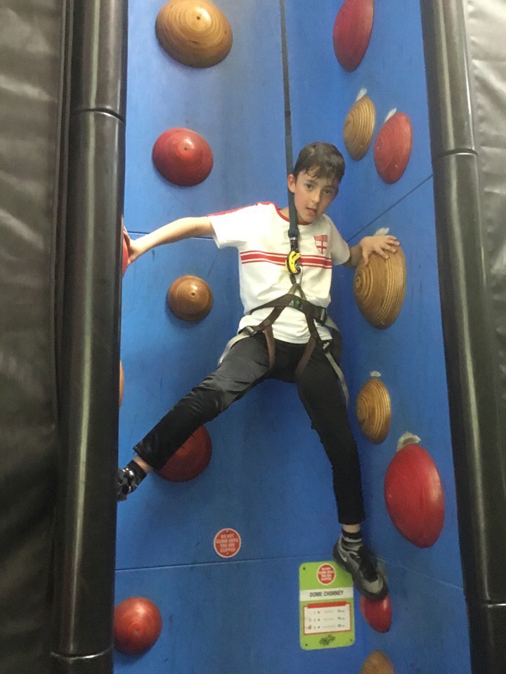 Young boy climbing up an indoor rock climbing wall