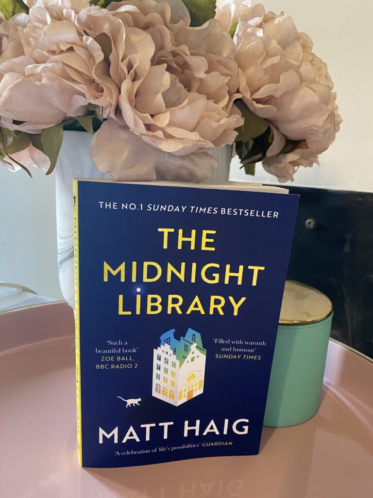 Book with pink flowers in a vase and a candle on pink tray