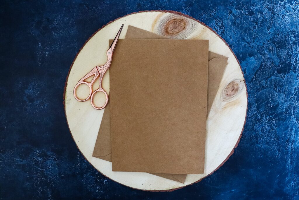 Kraft paper on wooden disc and rose gold scissors
