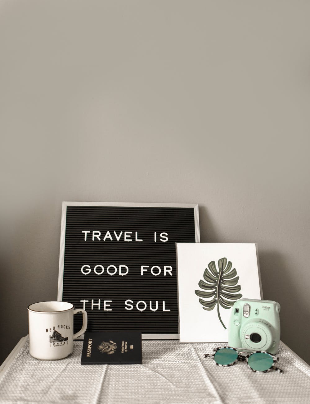 teal fujifilm instax mini camera near white ceramic mug Live to travel