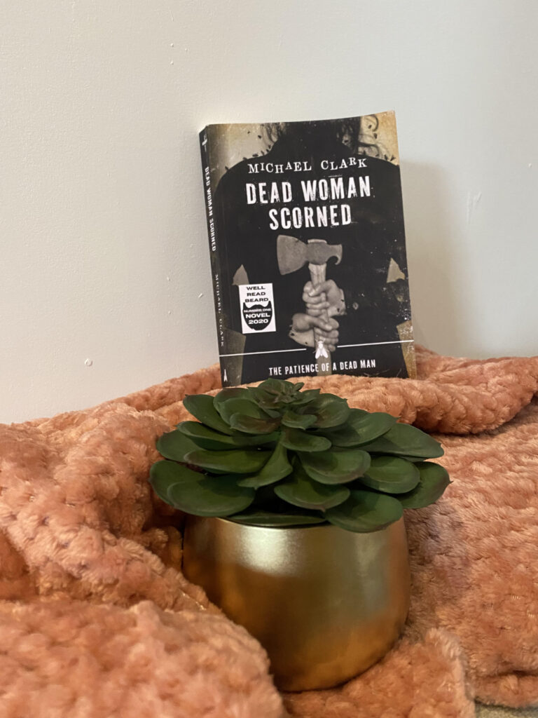 Gold pot with succulent on a pink waffle blanket and a book