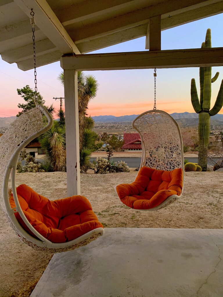 Two hanging chairs overlooking mountains and sunset