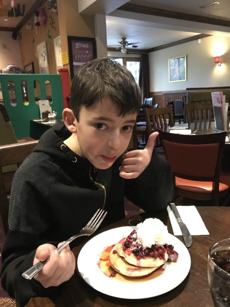 Boy eating pancakes with ice cream at a brown table giving a thumbs up Review 1 of 2019